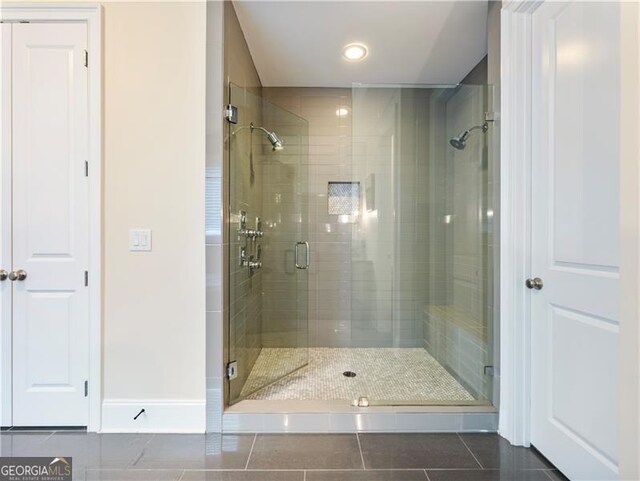 bathroom with a stall shower, tile patterned flooring, and baseboards