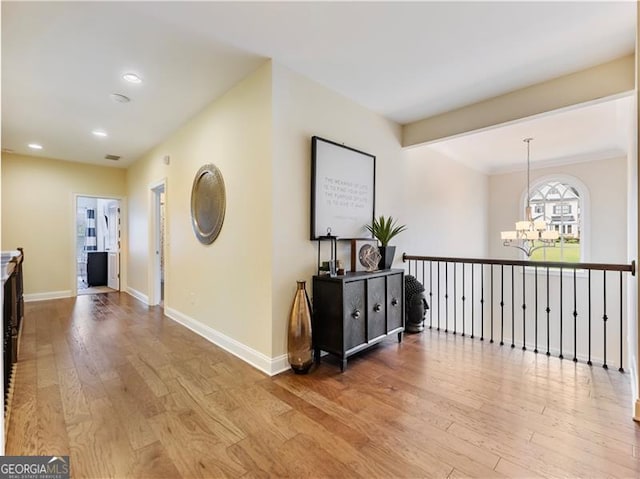 hall with light wood finished floors, baseboards, a notable chandelier, and recessed lighting