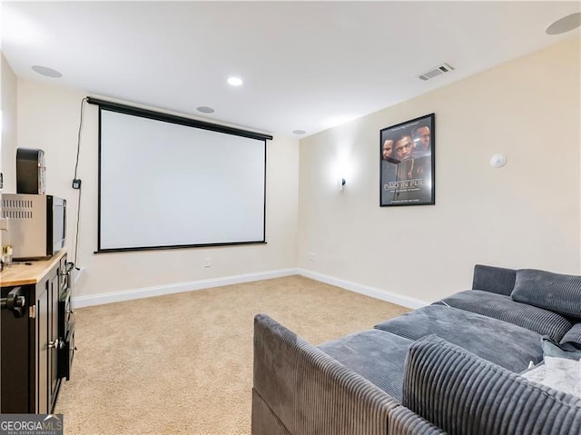 home theater featuring baseboards, visible vents, and light colored carpet