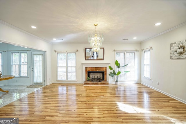 unfurnished living room featuring crown molding, a chandelier, a fireplace, and light hardwood / wood-style floors