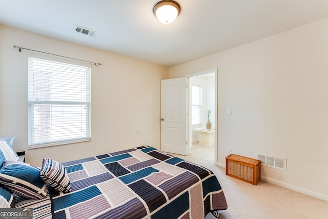 carpeted bedroom featuring multiple windows and connected bathroom