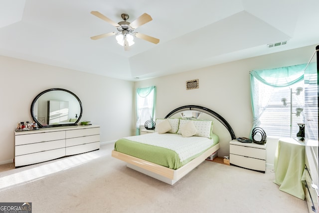 carpeted bedroom featuring ceiling fan and a tray ceiling