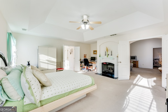 bedroom with a tray ceiling, ceiling fan, and carpet floors