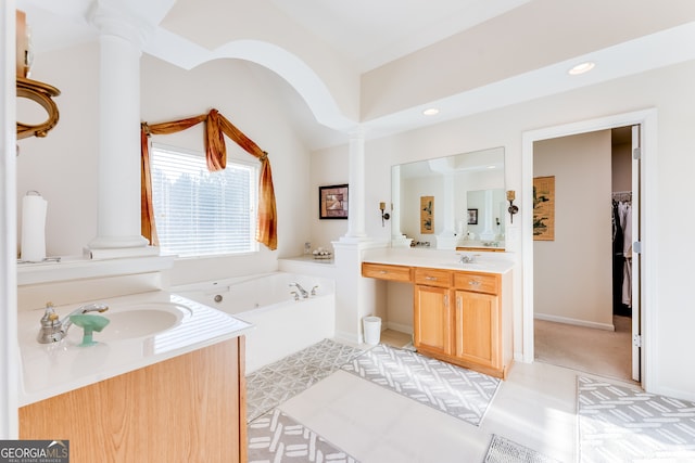 bathroom with ornate columns, vanity, and a bath