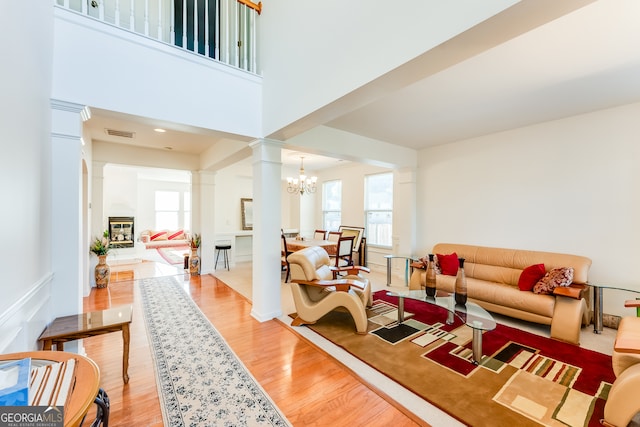 living room with hardwood / wood-style flooring, a healthy amount of sunlight, a chandelier, and decorative columns