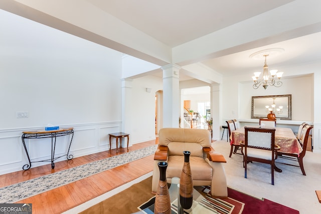 living room featuring hardwood / wood-style floors, a chandelier, and ornate columns