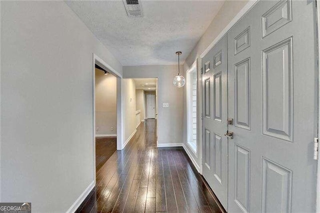 corridor featuring dark wood-type flooring and a textured ceiling