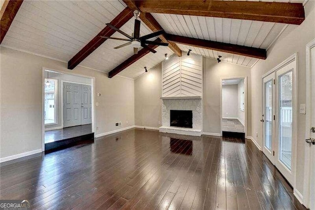 unfurnished living room with dark hardwood / wood-style flooring, wood ceiling, ceiling fan, lofted ceiling with beams, and a large fireplace