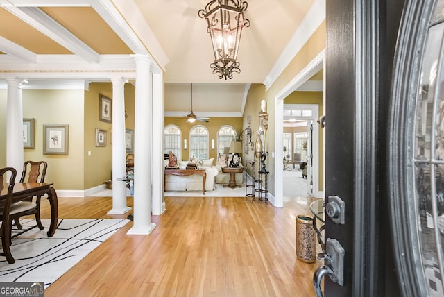 entrance foyer featuring ornamental molding, wood-type flooring, ornate columns, and ceiling fan with notable chandelier