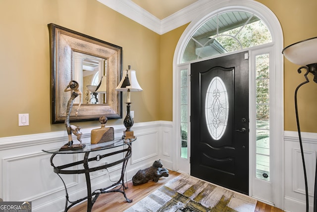 foyer featuring wood-type flooring and crown molding