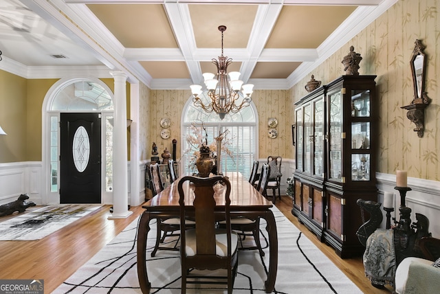 dining space featuring ornate columns, beam ceiling, coffered ceiling, an inviting chandelier, and light hardwood / wood-style floors