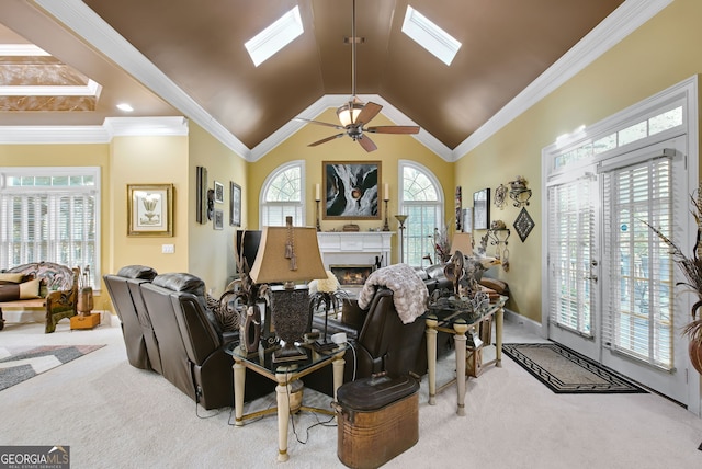 living room featuring crown molding, high vaulted ceiling, a skylight, light colored carpet, and ceiling fan