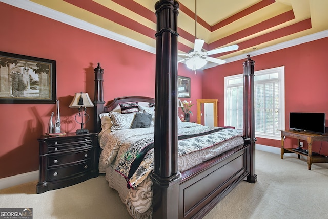 carpeted bedroom with a tray ceiling, ceiling fan, and crown molding