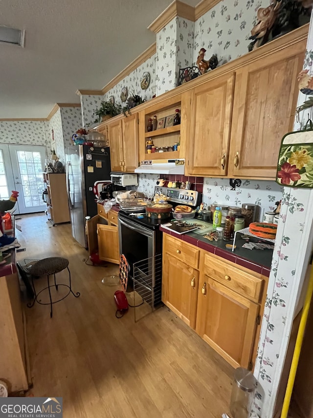 kitchen featuring appliances with stainless steel finishes, tile counters, light hardwood / wood-style floors, and crown molding