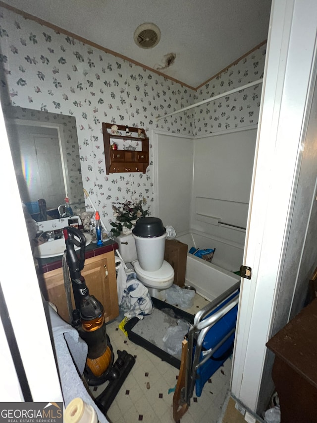 bathroom featuring toilet, shower / bathtub combination, and a textured ceiling