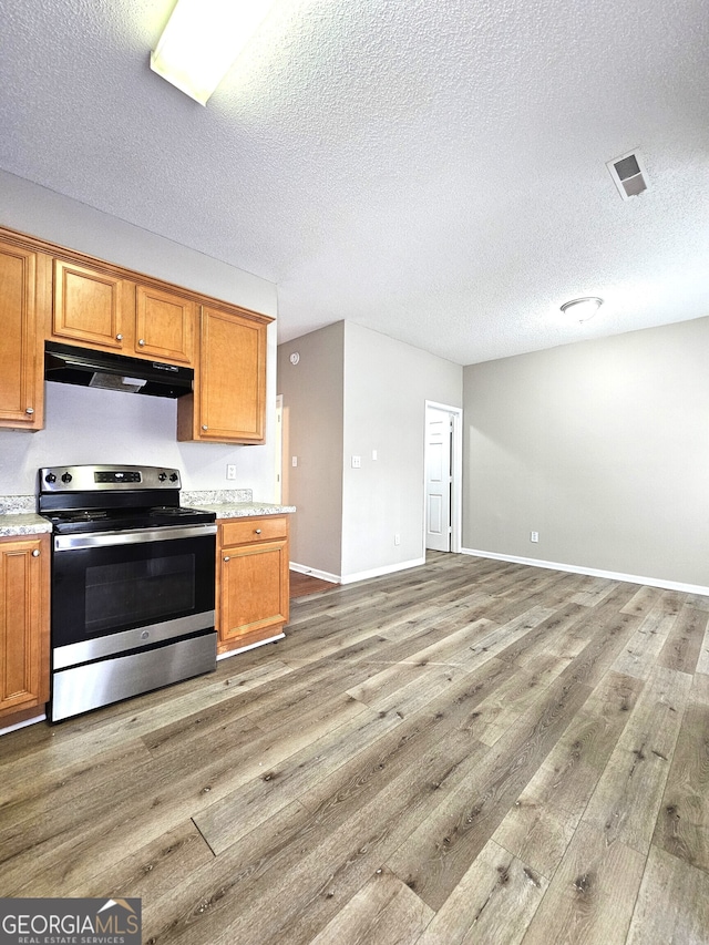 kitchen featuring hardwood / wood-style floors, a textured ceiling, and stainless steel range with electric stovetop