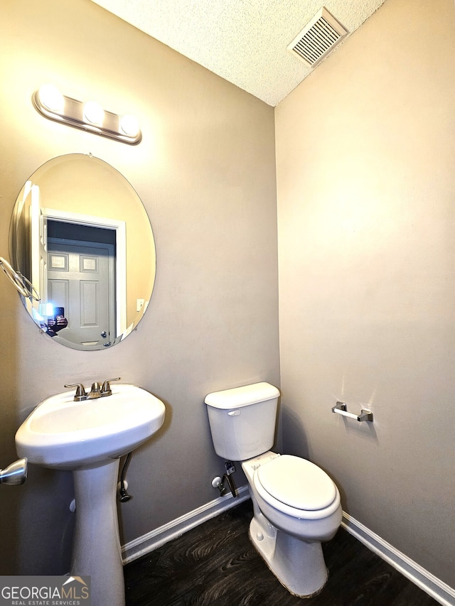 bathroom with toilet, hardwood / wood-style floors, and a textured ceiling