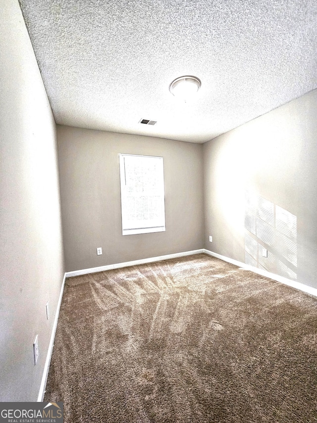 unfurnished room with a textured ceiling and carpet