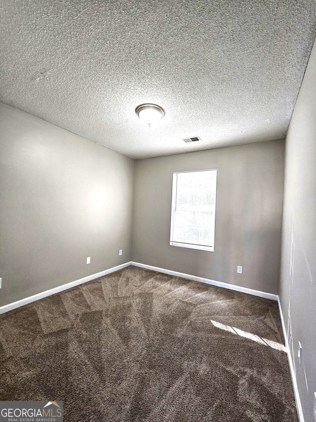 empty room with a textured ceiling and carpet flooring