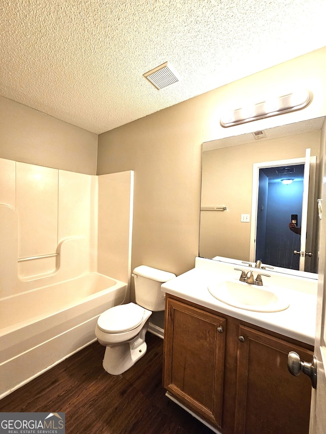 full bathroom featuring wood-type flooring, toilet, a textured ceiling, vanity, and shower / tub combination