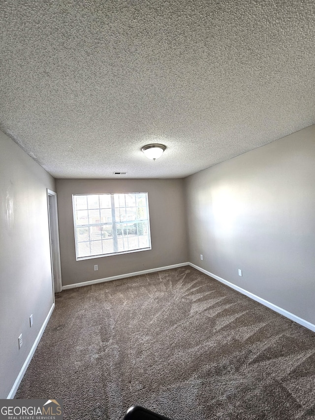 carpeted empty room with a textured ceiling