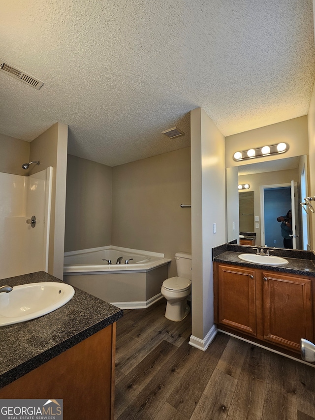 full bathroom with shower with separate bathtub, vanity, a textured ceiling, hardwood / wood-style flooring, and toilet