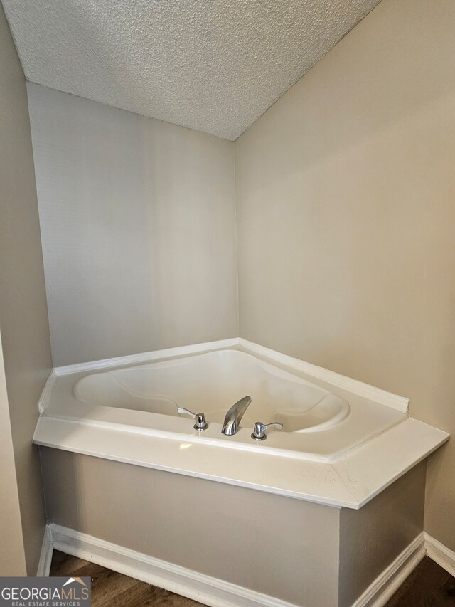 bathroom featuring a textured ceiling, hardwood / wood-style flooring, and a tub