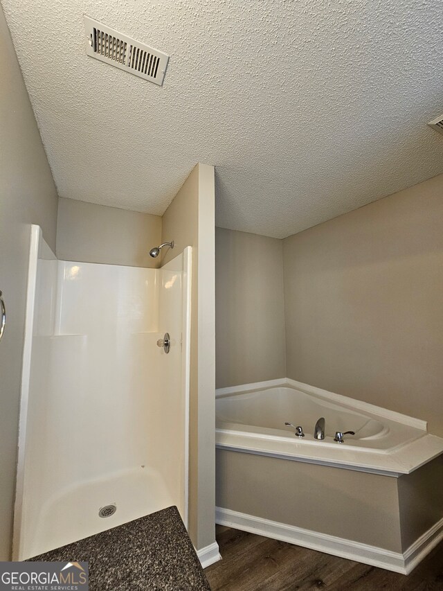 bathroom featuring independent shower and bath, wood-type flooring, and a textured ceiling