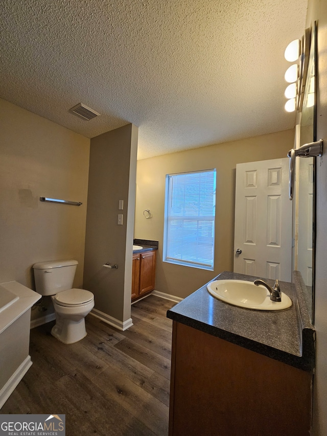 bathroom with hardwood / wood-style floors, vanity, a textured ceiling, and toilet