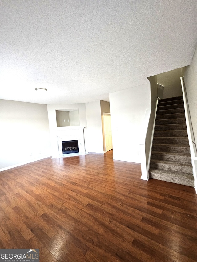 unfurnished living room featuring dark wood-type flooring and a textured ceiling