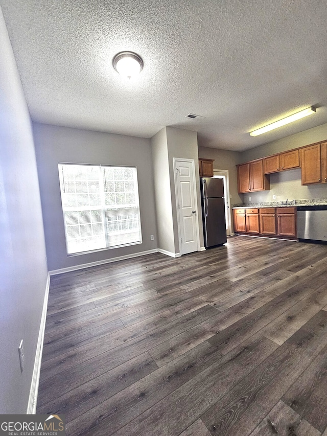 kitchen featuring stainless steel appliances, a textured ceiling, and dark hardwood / wood-style flooring