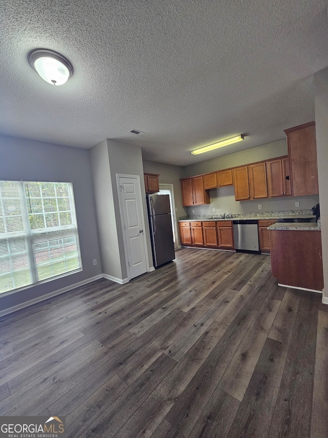 kitchen with appliances with stainless steel finishes, a textured ceiling, sink, and dark hardwood / wood-style flooring