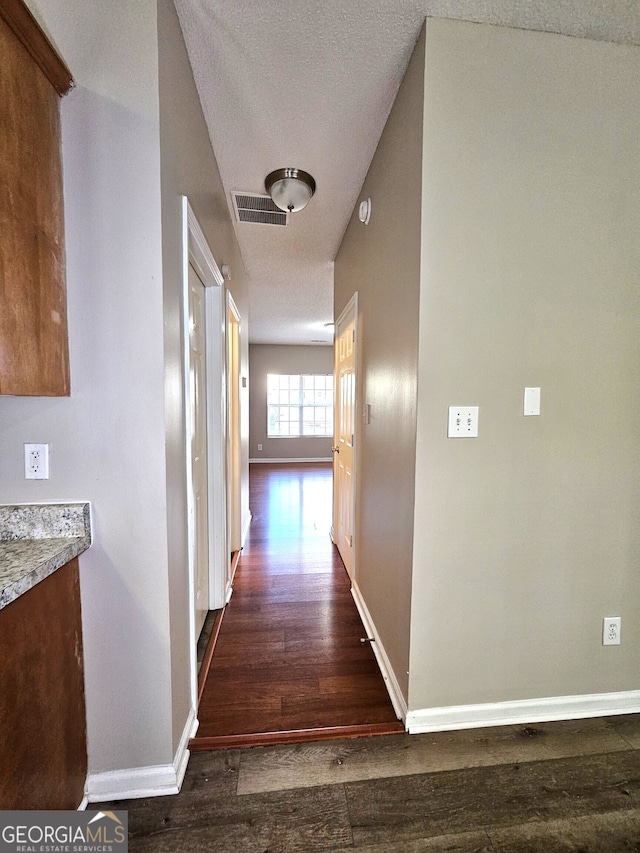 hallway featuring a textured ceiling and dark hardwood / wood-style flooring