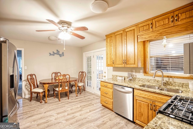 kitchen featuring stainless steel appliances, light wood-type flooring, light stone countertops, sink, and ceiling fan