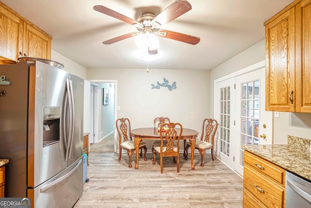 kitchen featuring light wood-type flooring, stainless steel appliances, ceiling fan, and light stone counters