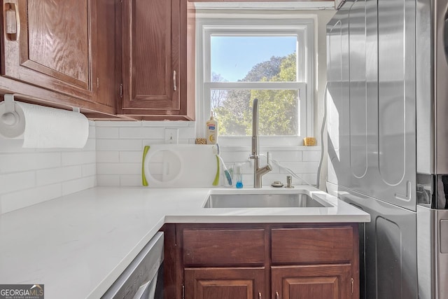 kitchen featuring white dishwasher, stacked washer / drying machine, and sink