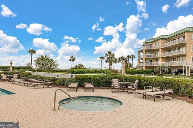 view of swimming pool featuring a hot tub and a patio area