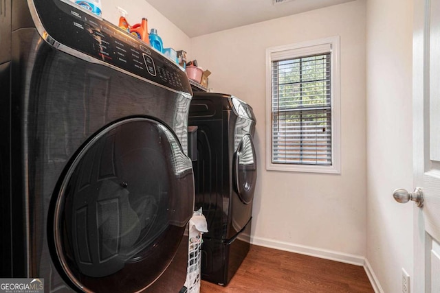 clothes washing area featuring wood-type flooring and washer and dryer