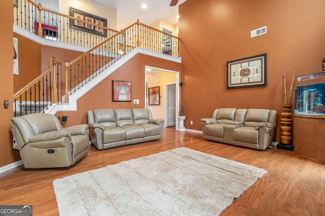 living room with hardwood / wood-style floors, ceiling fan, and a towering ceiling