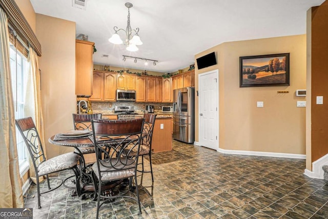 kitchen with stainless steel appliances, kitchen peninsula, backsplash, decorative light fixtures, and a notable chandelier