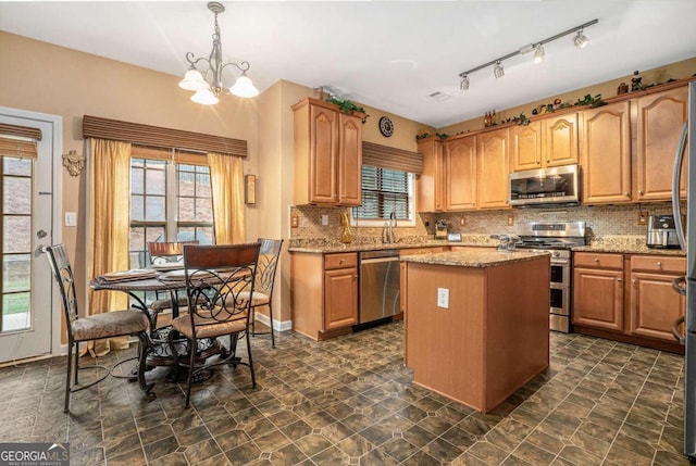 kitchen featuring pendant lighting, appliances with stainless steel finishes, light stone counters, and a healthy amount of sunlight