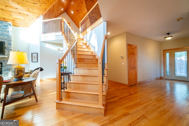 stairway with hardwood / wood-style flooring, wood ceiling, a fireplace, and high vaulted ceiling