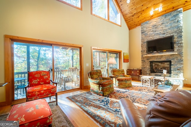 living room with hardwood / wood-style floors, wooden ceiling, a fireplace, and high vaulted ceiling