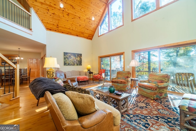 living room with a wealth of natural light, light wood-type flooring, high vaulted ceiling, and an inviting chandelier