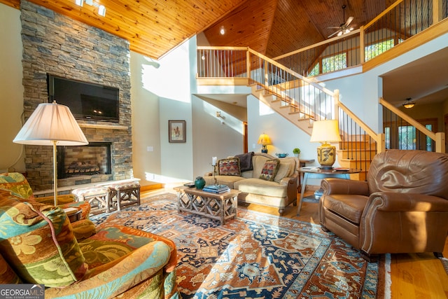 living room with ceiling fan, wooden ceiling, high vaulted ceiling, hardwood / wood-style floors, and a fireplace