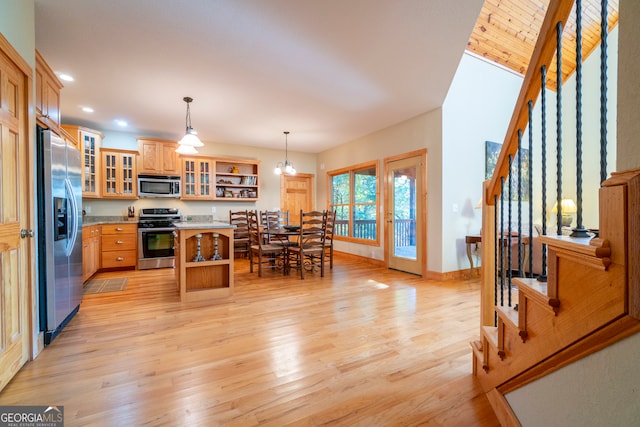 kitchen with hanging light fixtures, a breakfast bar area, a kitchen island, light hardwood / wood-style floors, and stainless steel appliances