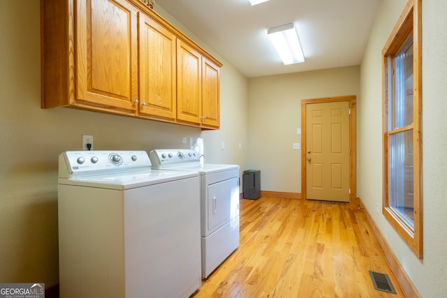 laundry room with cabinets, light wood-type flooring, and separate washer and dryer