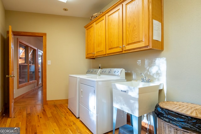 washroom with washer and dryer, light hardwood / wood-style flooring, cabinets, and sink