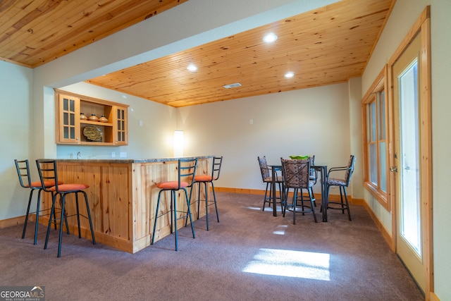 kitchen with a breakfast bar area, kitchen peninsula, wood ceiling, and dark carpet