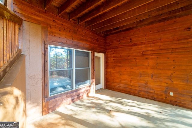 interior space featuring beam ceiling and wooden walls